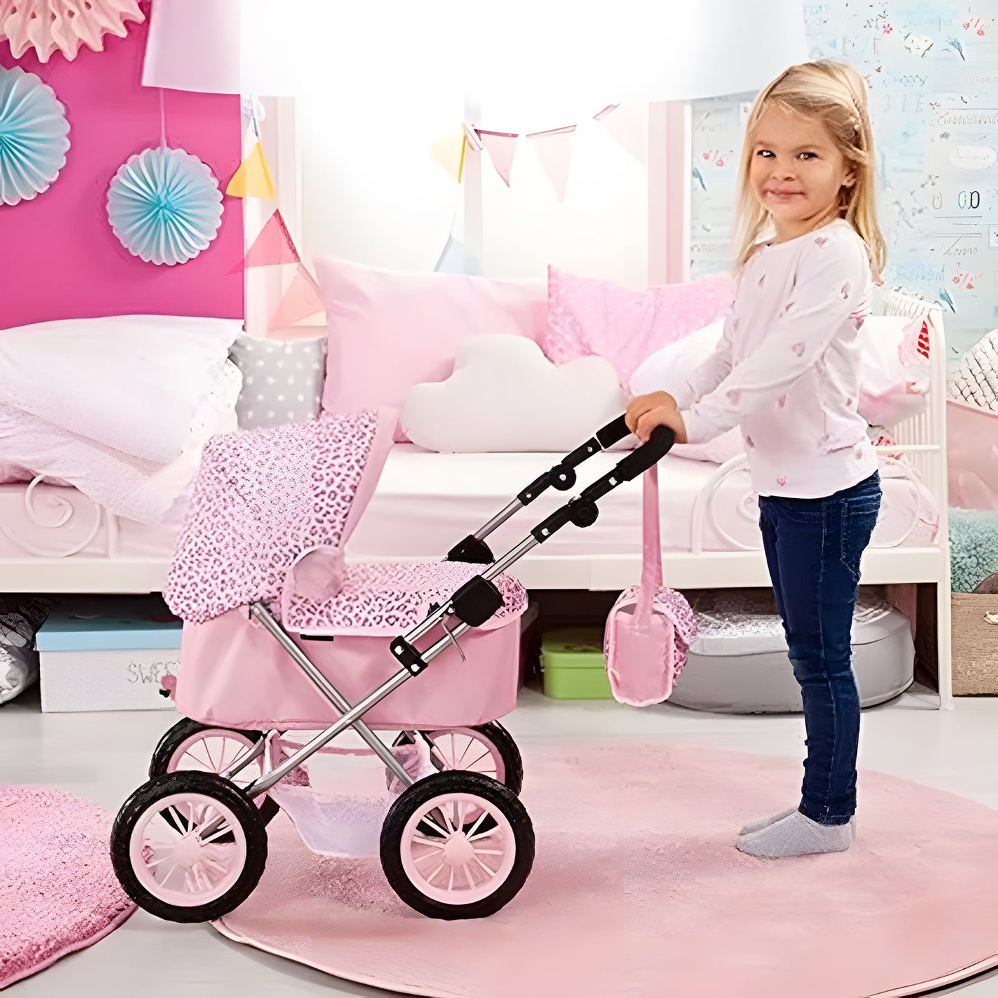 A young girl with blonde hair stands next to a pink toy baby stroller in a decorated children's bedroom. The stroller has a pink leopard-print fabric canopy and seat, a silver metal frame, and black wheels.
