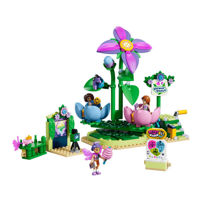 A colorful toy building block set featuring a fantasy flower garden scene with a large purple and pink flower, green stems, small character figures, a treehouse-like structure, and decorative signs on a plain white background.